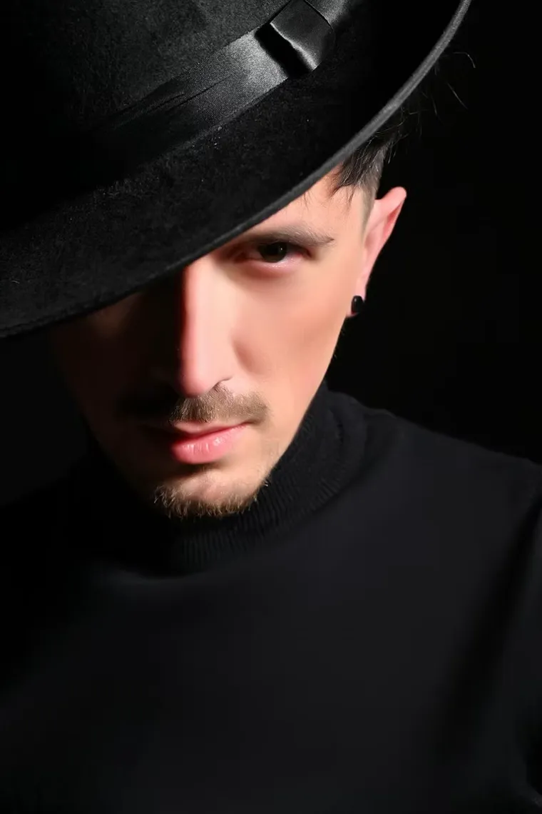 A male client photographed in a hat under hard studio light